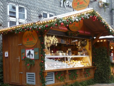 Das Tiroler Weihnachtsmarkthäuschen direkt vor dem Glockenspiel des Marktplatzes